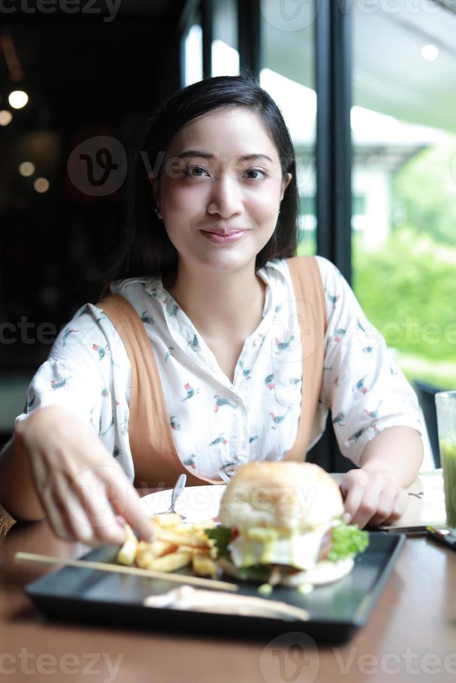 Mujeres asiáticas sonrientes y felices y disfrutaron comiendo hamburguesas en el café y el restaurante en el momento de relajarse foto