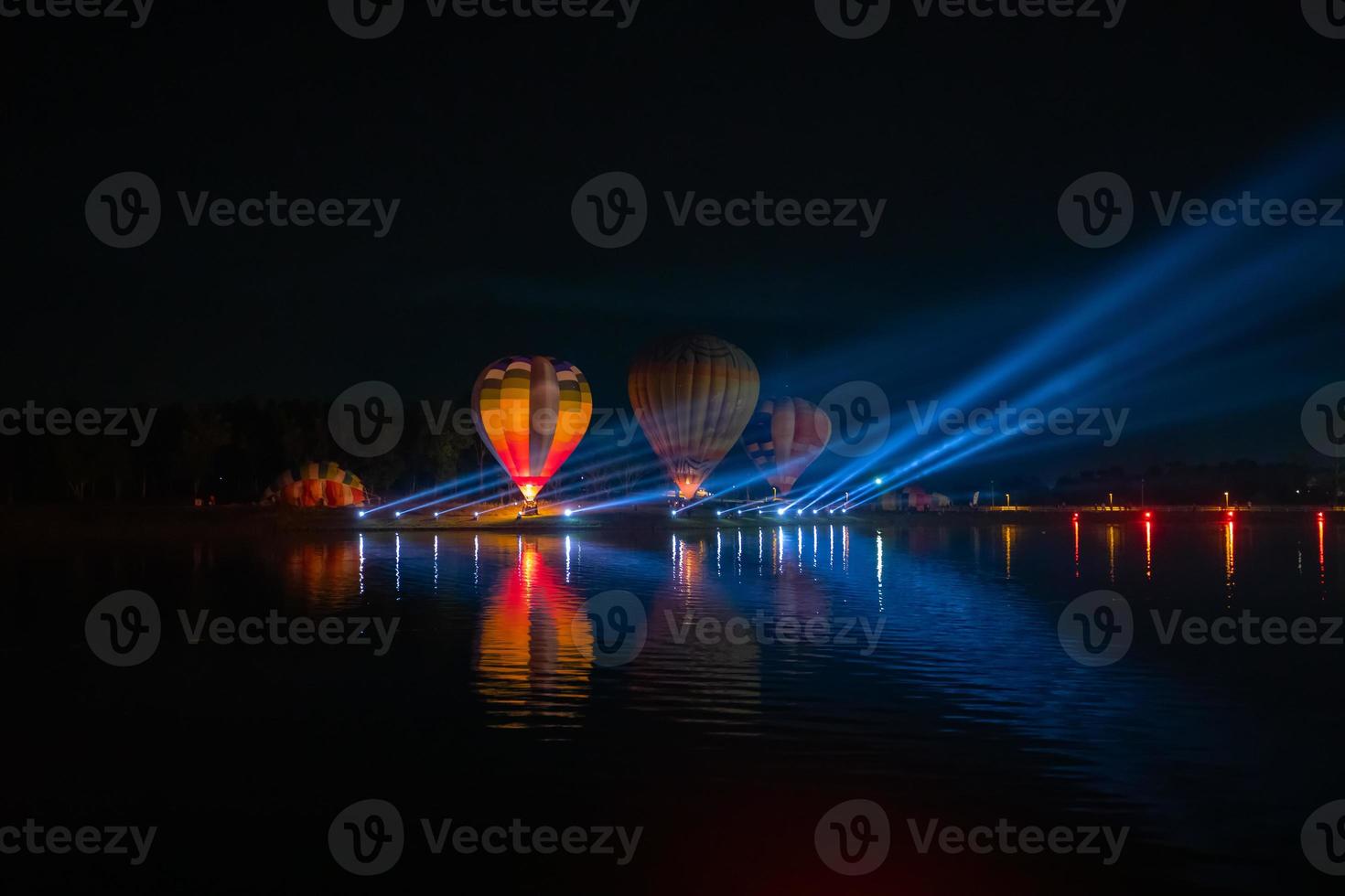 coloridos globos aerostáticos volando sobre el río en el festival nocturno foto