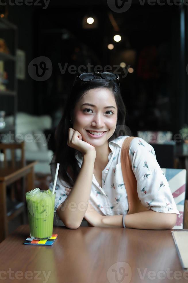 Asian women smiling and happy Relaxing with green tea in a coffee shop photo