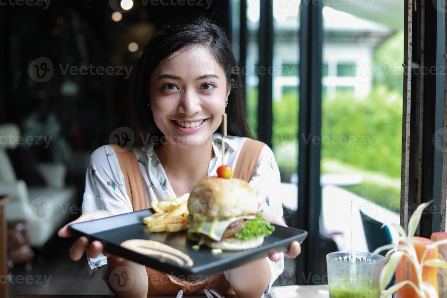 Mujeres asiáticas sonrientes y felices y disfrutaron comiendo hamburguesas en el café y el restaurante en el momento de relajarse foto