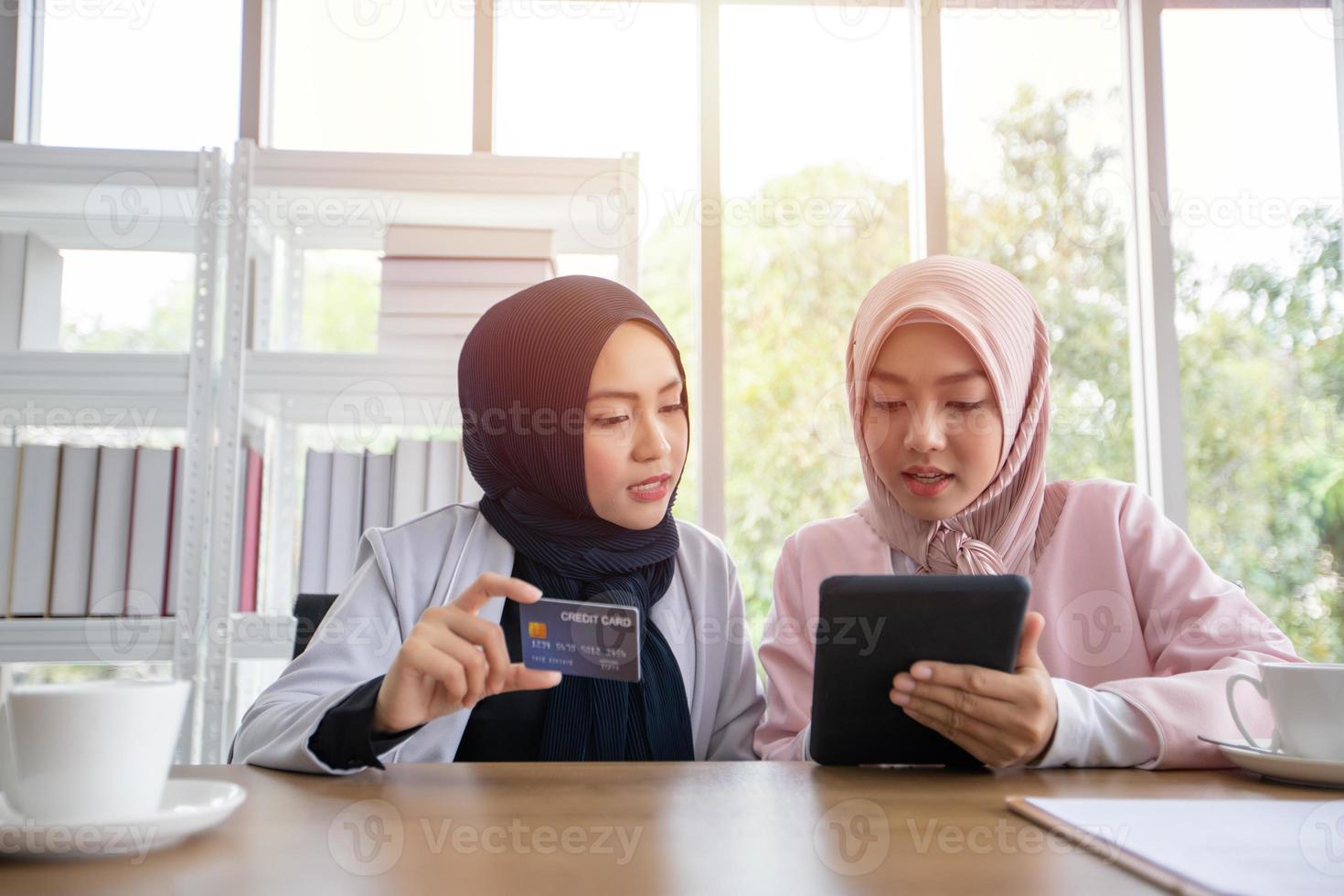 Muslim business woman in traditional clothing shopping online and paying with credit card photo