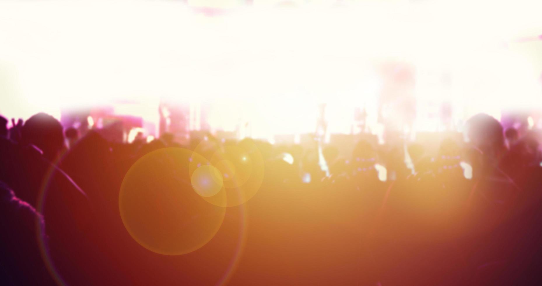 silhouettes of concert crowd at Rear view of festival crowd raising their hands on bright stage lights photo