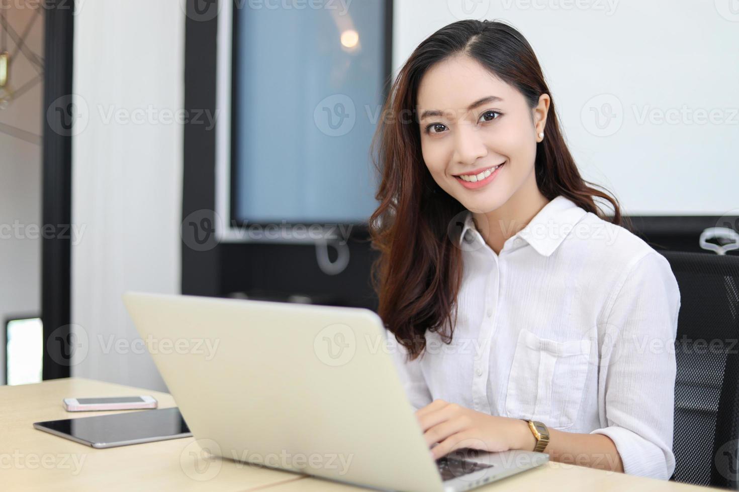 Mujeres de negocios asiáticas que usan el cuaderno y sonríen felices por trabajar foto