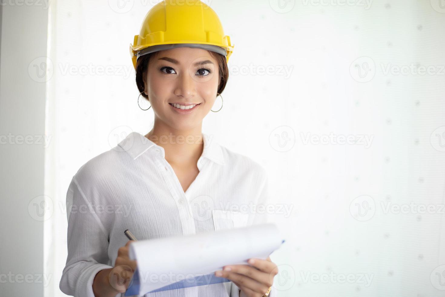 Mujeres asiáticas de ingeniería inspeccionando y trabajando y sosteniendo planos en la oficina foto