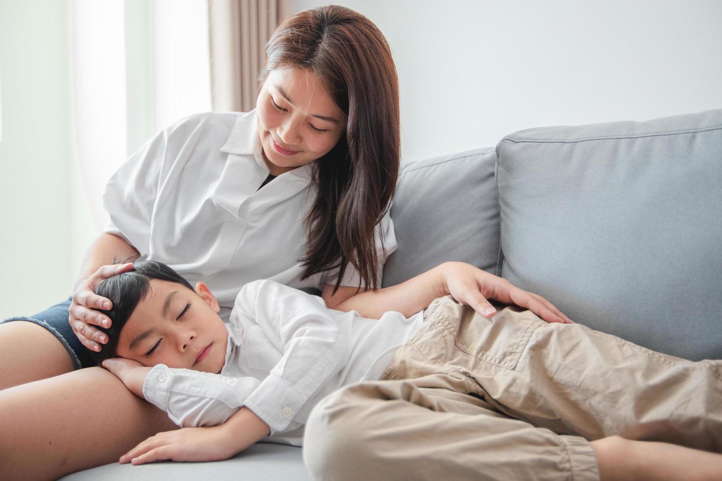 niño feliz a la hora de acostarse durmiendo en el sofá con mamá foto