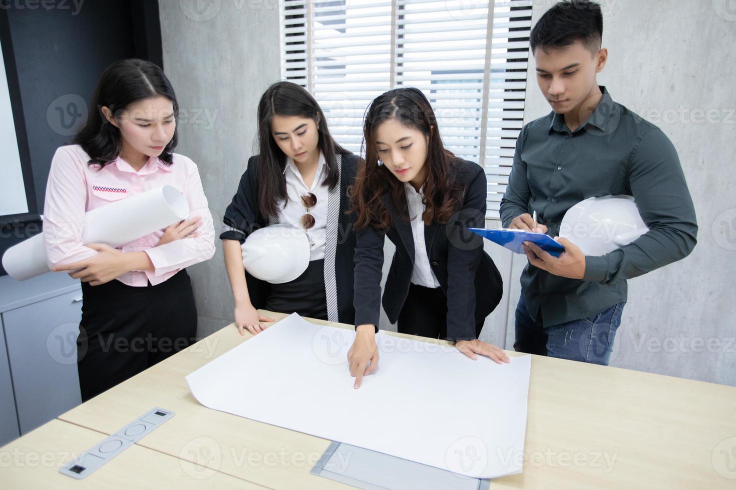 Grupo de hombres de negocios e ingenieros que usan un cuaderno para socios comerciales que discuten documentos e ideas en una reunión y mujeres de negocios que sonríen felices por trabajar foto