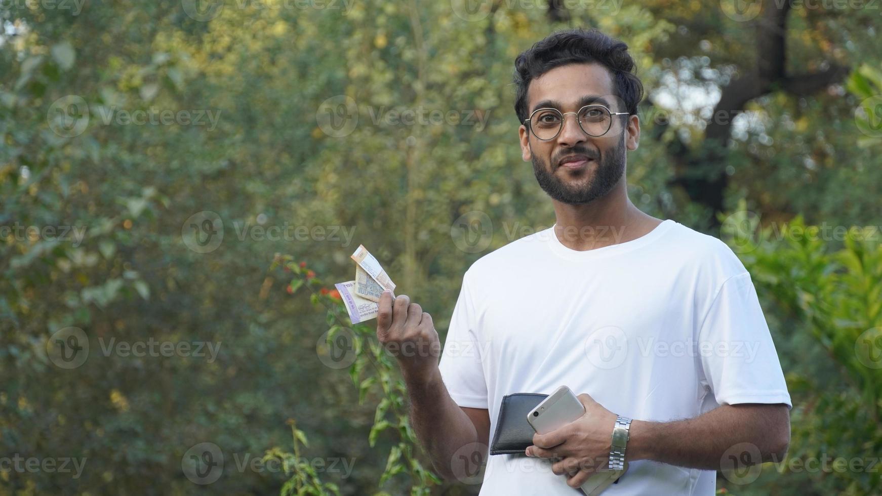 Indian Man With Cash Making Money Online On Mobile Phone, photo