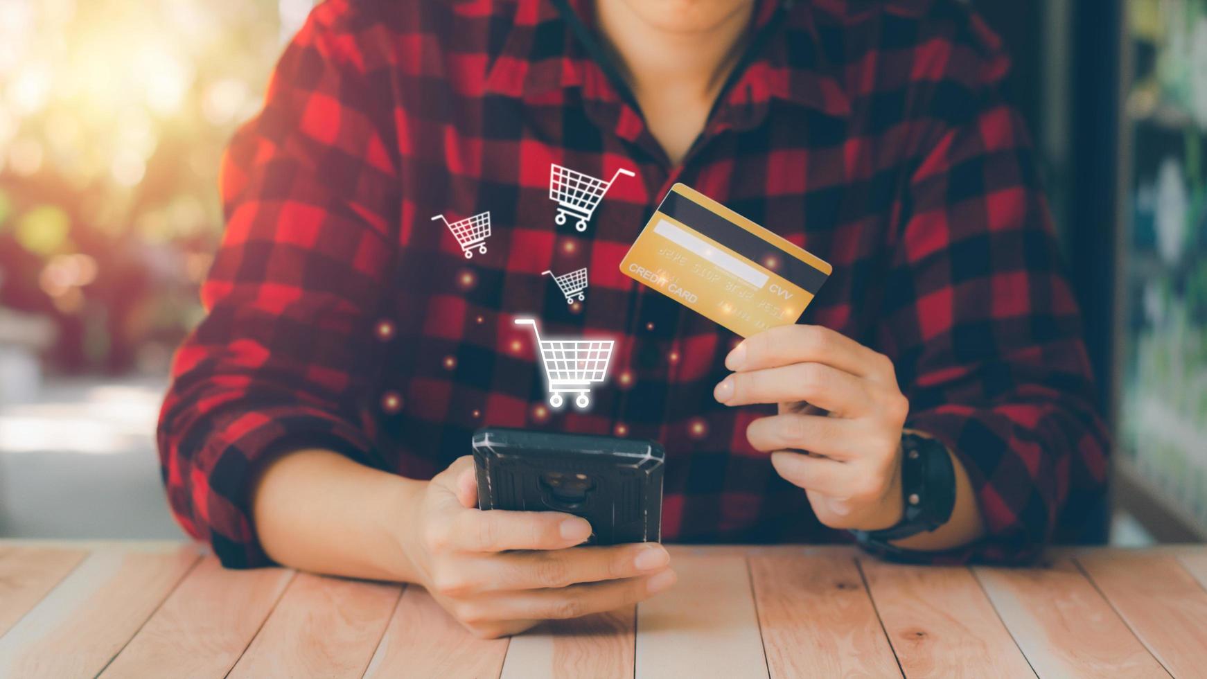 Online payment concept. Businessman holding a cell phone and credit cards with virtual screen shopping cart for online transactions, shopping, booking accommodation and hotel, e-commerce. photo