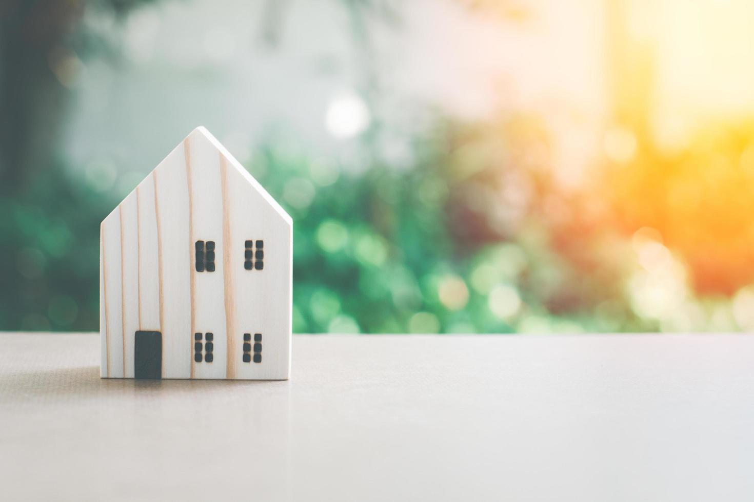 concepto de hogar ecológico. pequeño modelo de casa de madera con fondo verde natural bokeh con espacio de copia. foto