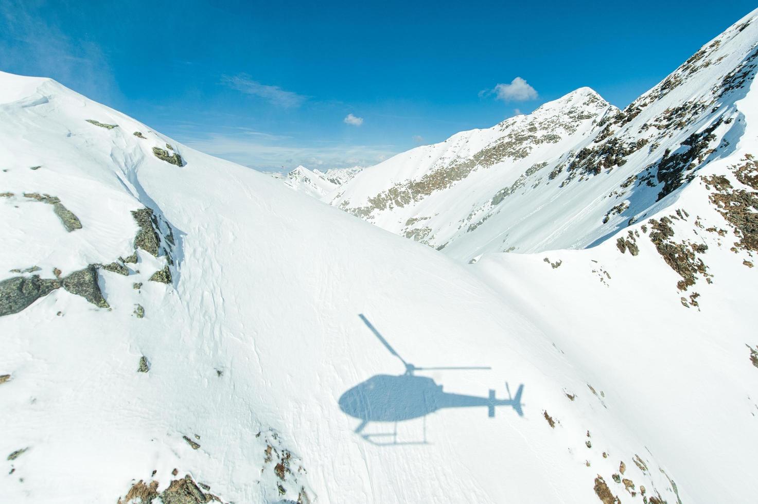 Helicopter shadow projected onto snow on mountains photo