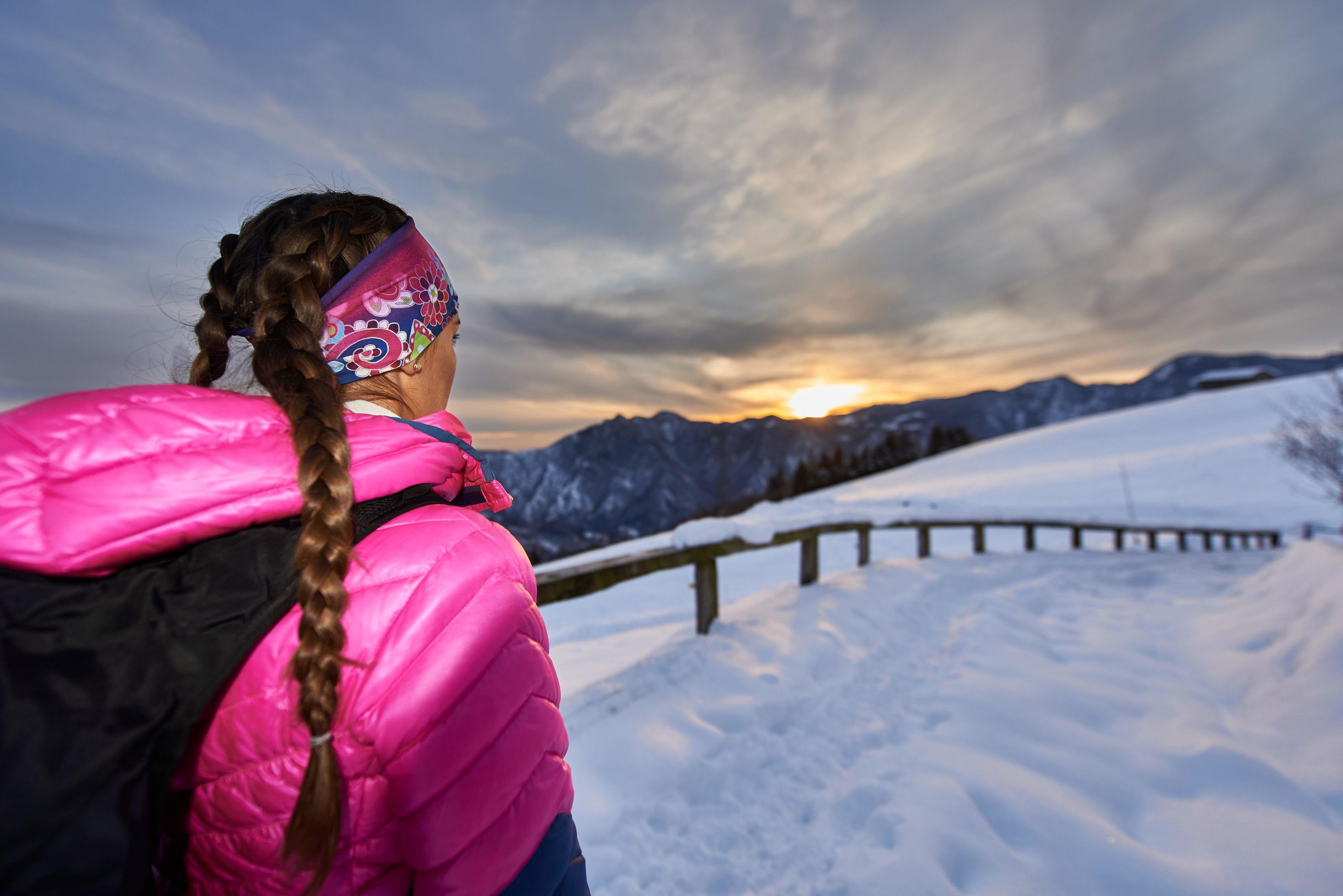 chica mira la puesta de sol en las montañas durante una caminata foto