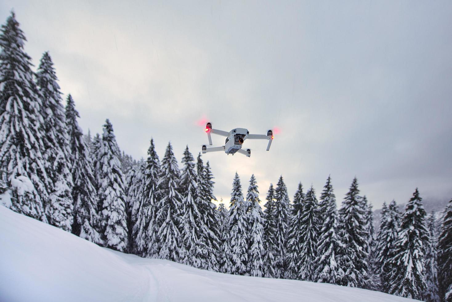 Drone just got up in flight after snowfall near trees photo