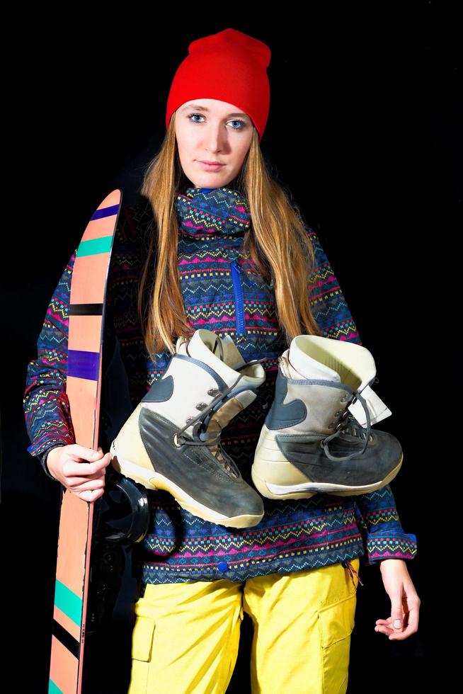 Sporty girl with snowboard equipment on black background in studio photo