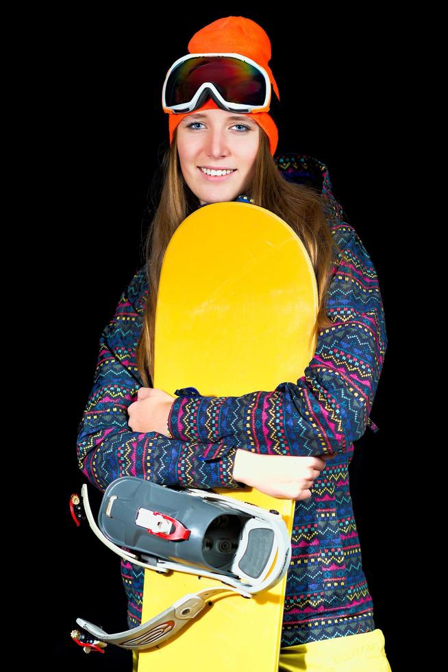 Sporty girl with snowboard on black background in studio photo