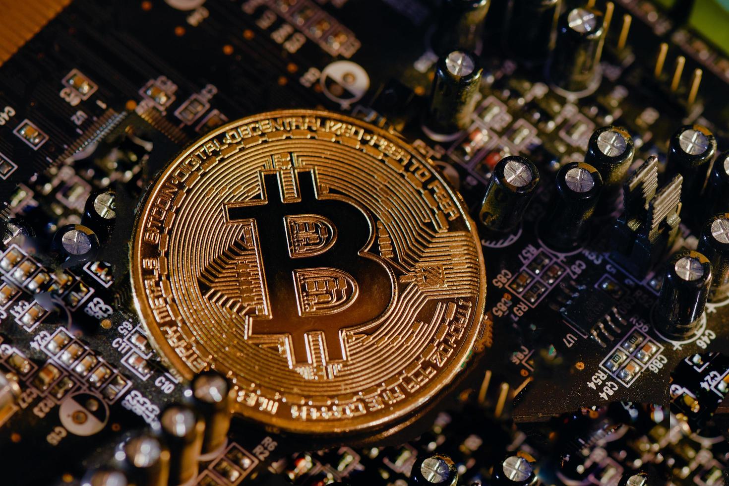 Physical Bitcoin coin resting on electronic circuits photo