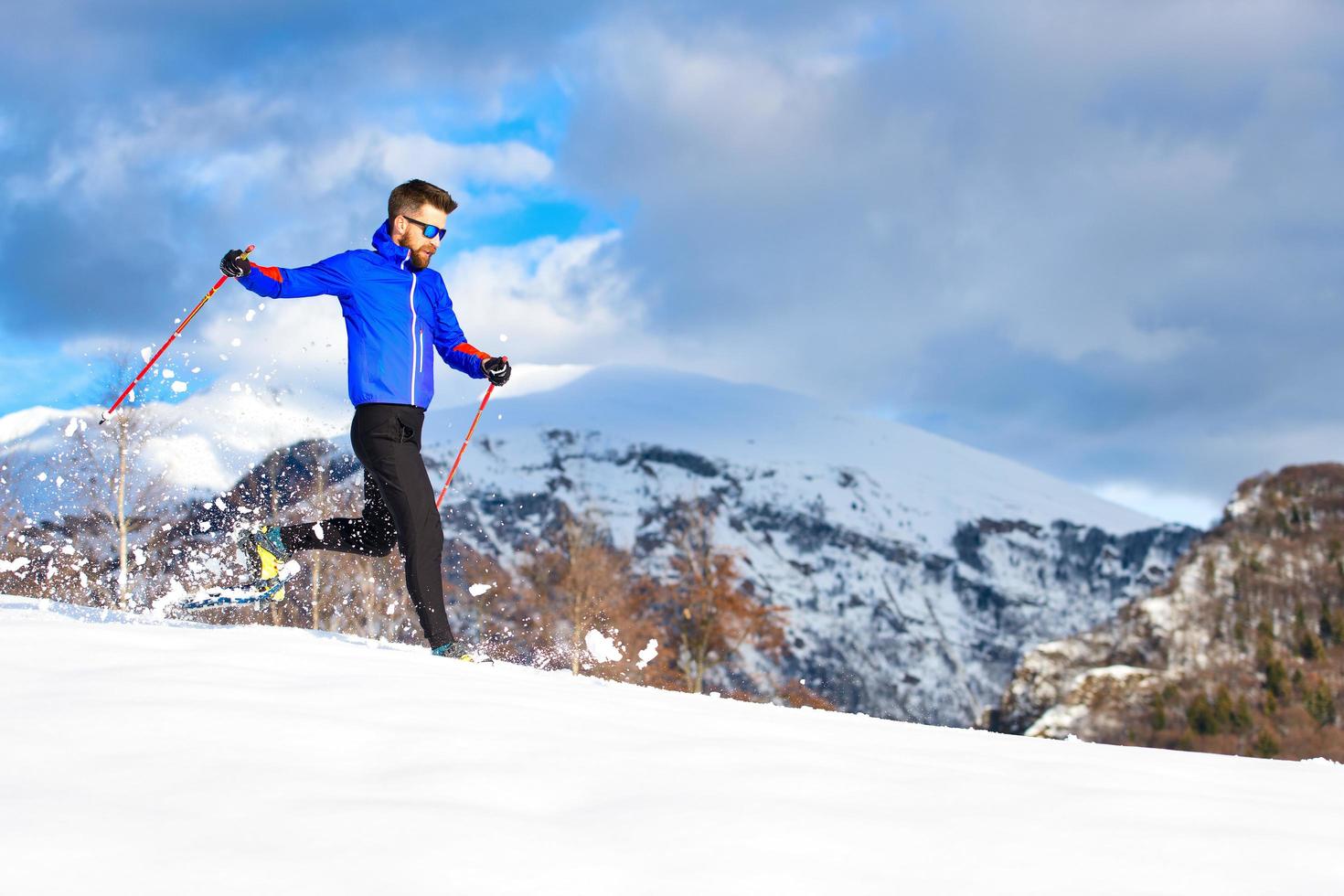 un hombre corriendo cuesta abajo con raquetas de nieve foto