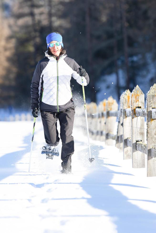 una niña durante un paseo con raquetas de nieve y bastones foto