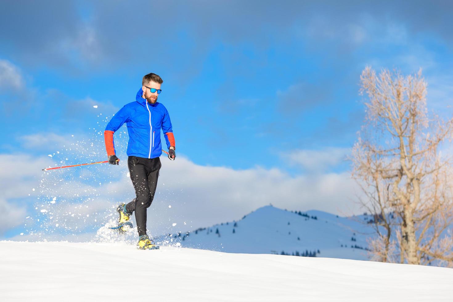 Runner with snowshoes downhill on a sunny day photo