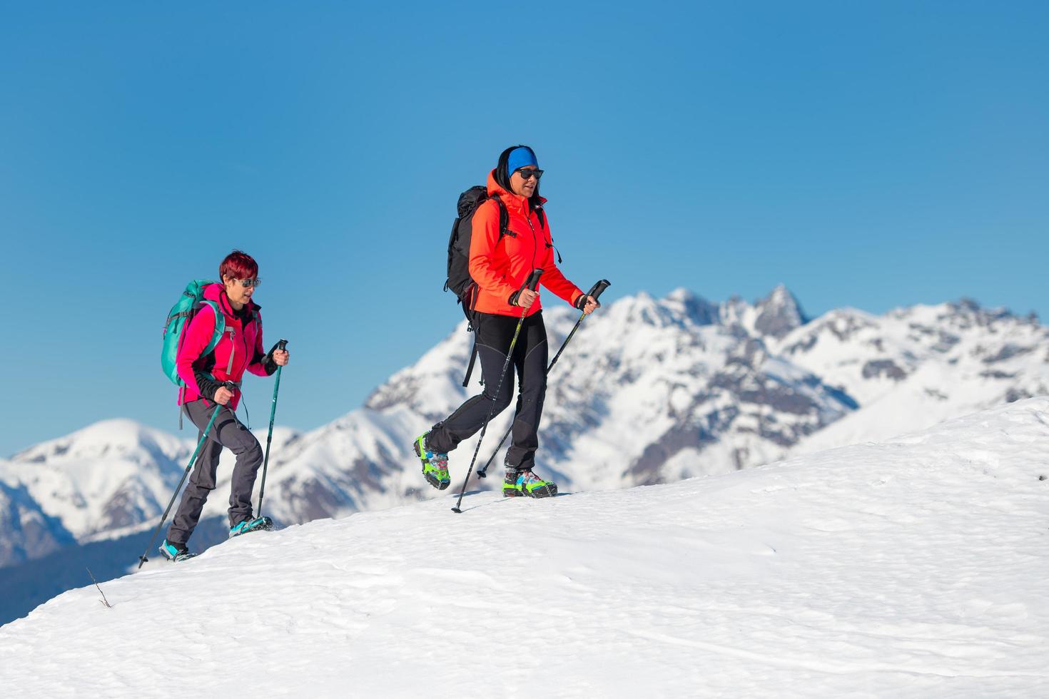 Two female mountaineer friends while climbing a mountain in winter photo