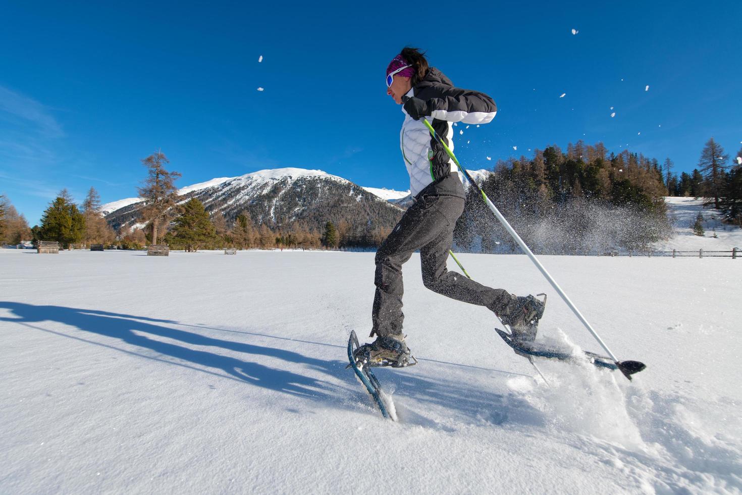 Girl in the snow runs with snowshoes photo