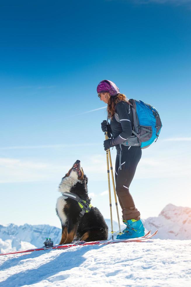 Girl on top of a mountain in winter with skiing and its Bernese dog photo