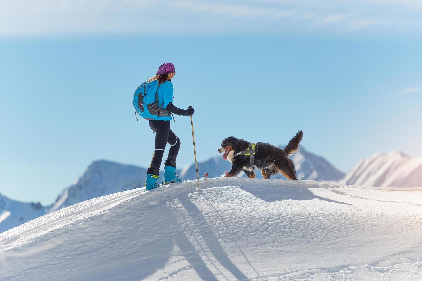 chica en la cima de una montaña con esquís y su perro foto