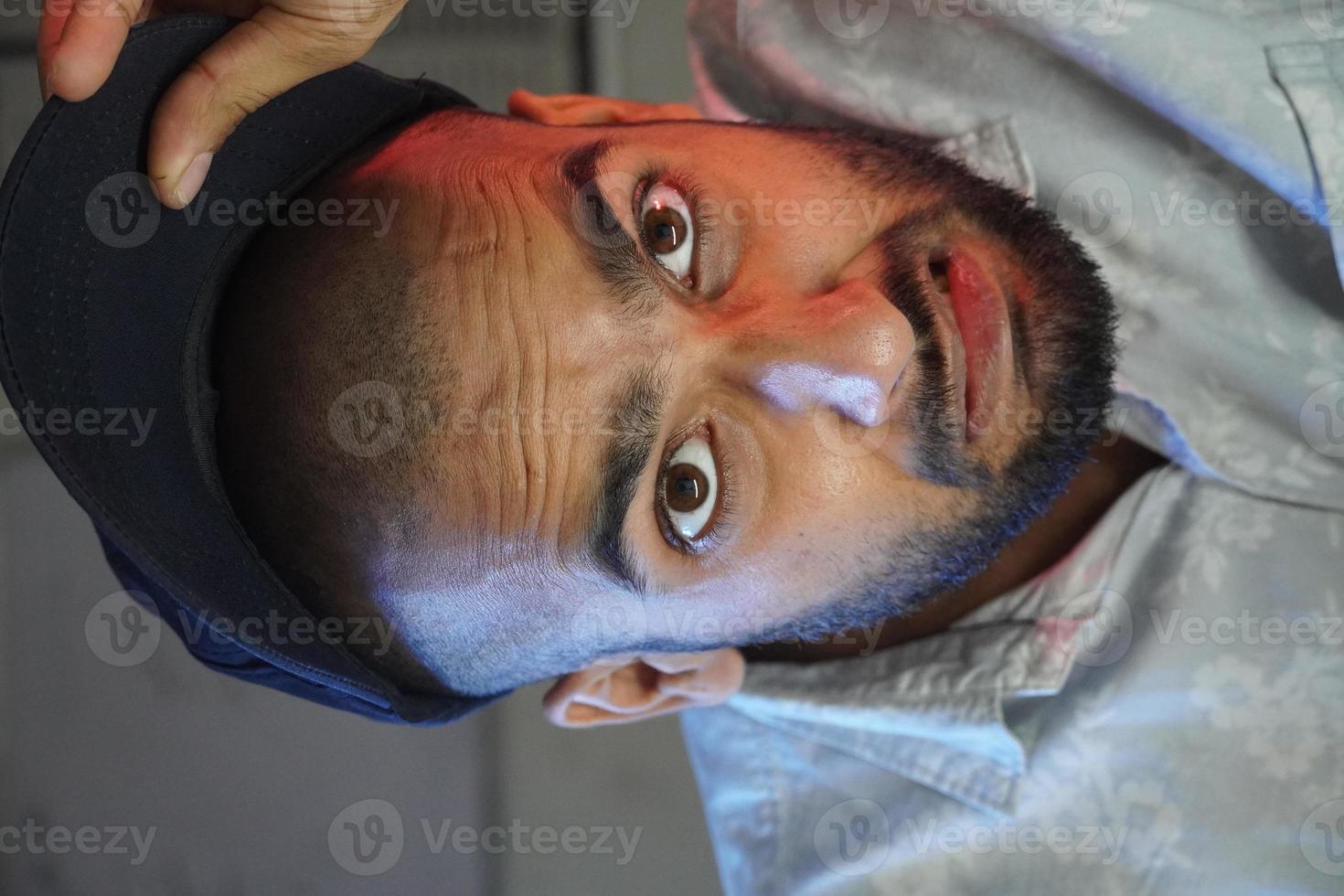 A bald young man shocked and trying to hide baldness using cap in front of camera photo