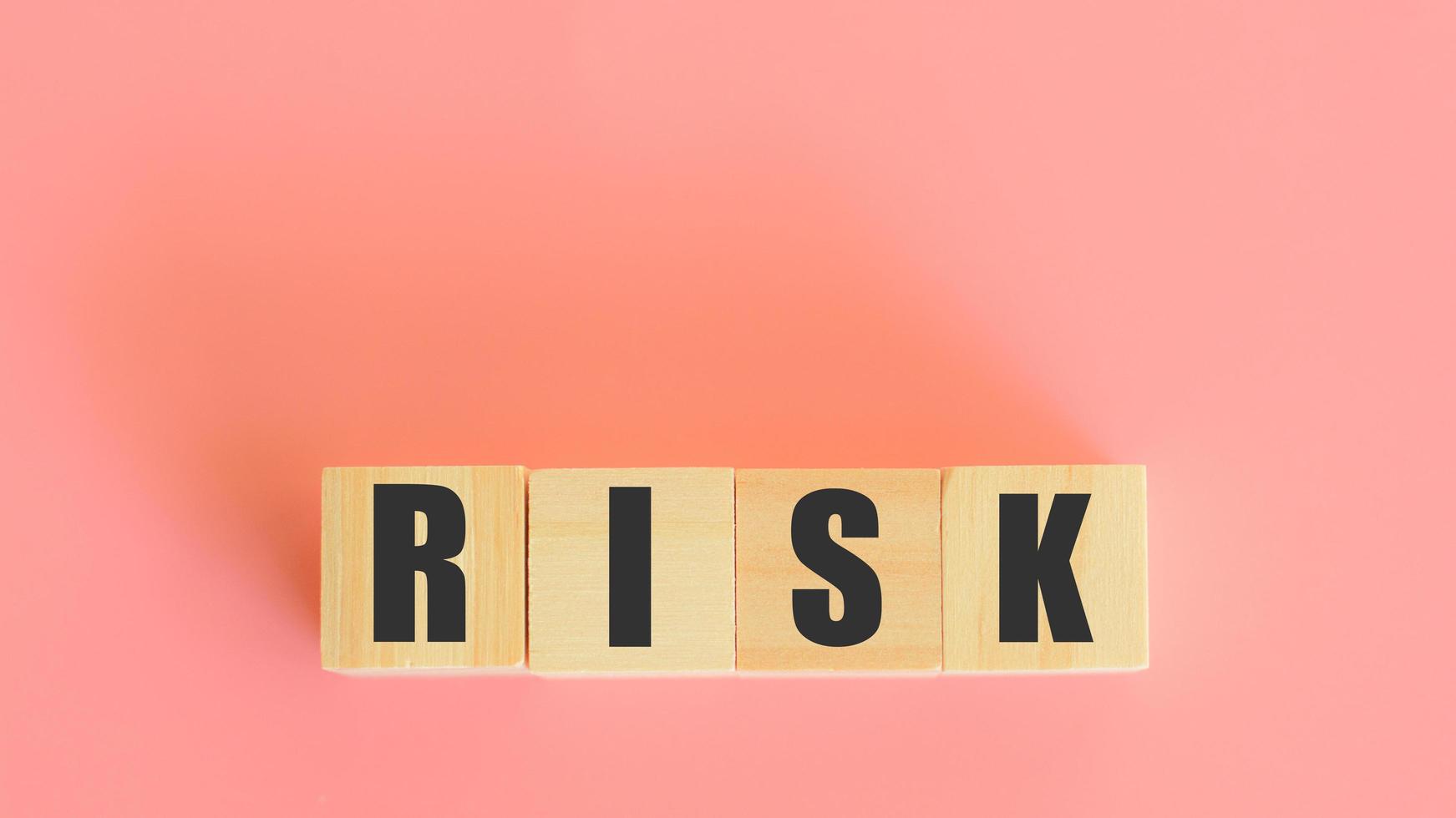 Risk assessment investment concept. Wooden block with risk word on pink background. Analysis and management of a business. photo