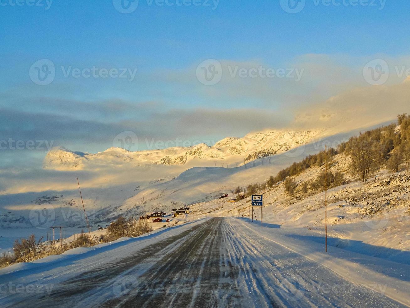 Driving at golden sunrise through mountains and village in Norway. photo