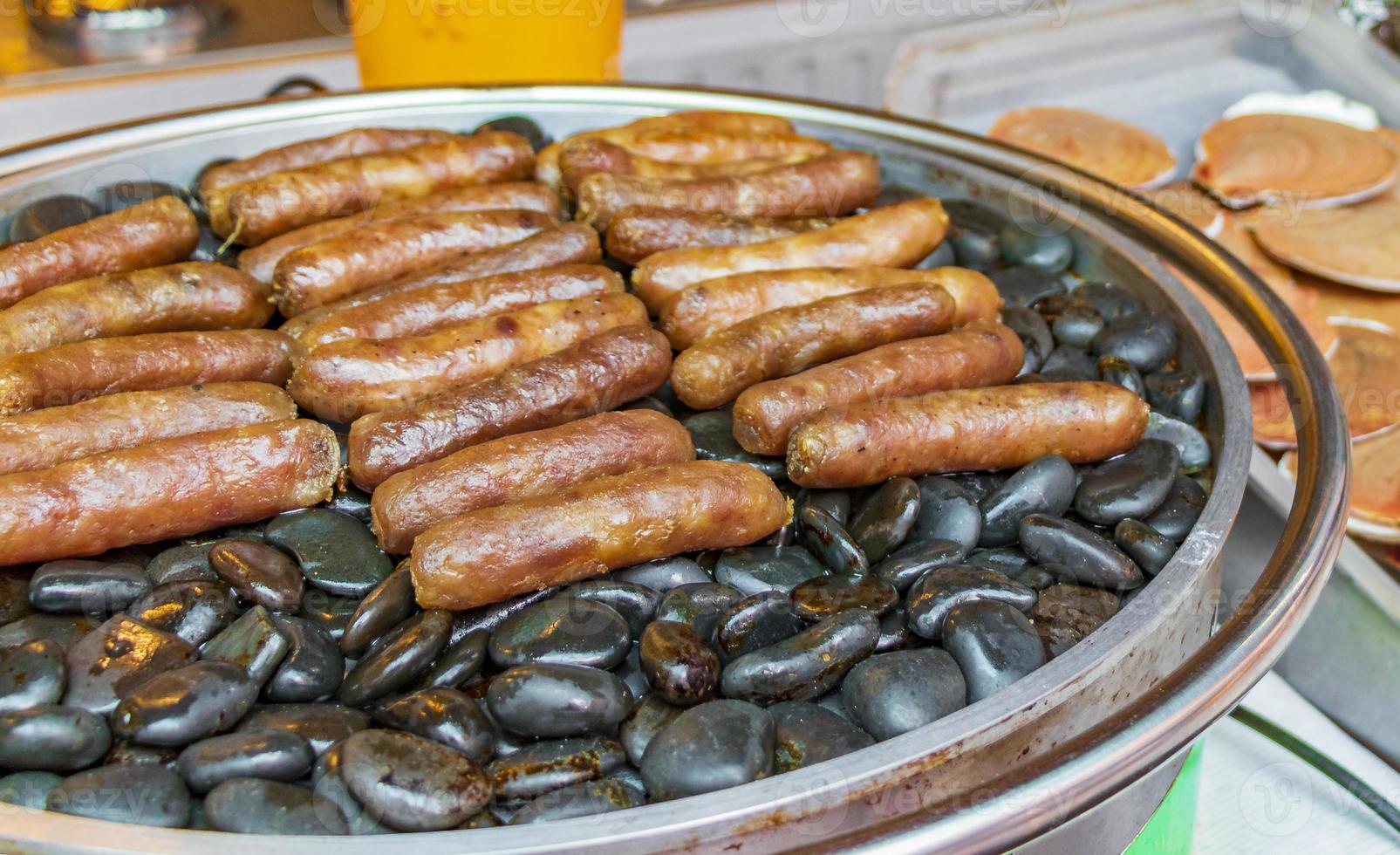 salchichas a la parrilla sobre piedras calientes mercado tailandés ciudad china bangkok. foto