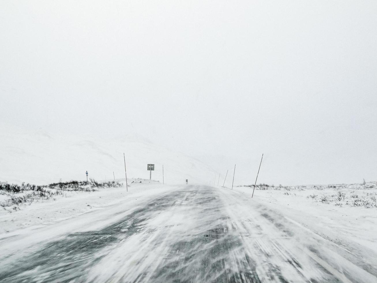 Driving through blizzard snowstorm with black ice on road, Norway. photo