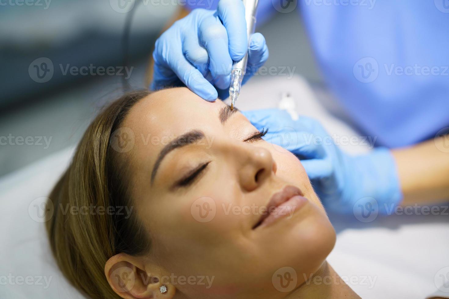 maquillaje permanente para cejas de mujer hermosa en un salón de belleza. tratamiento de micropigmentación. foto