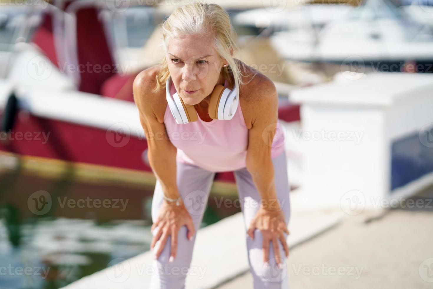 Senior woman in fitness clothing stretching her arms after exercise. photo