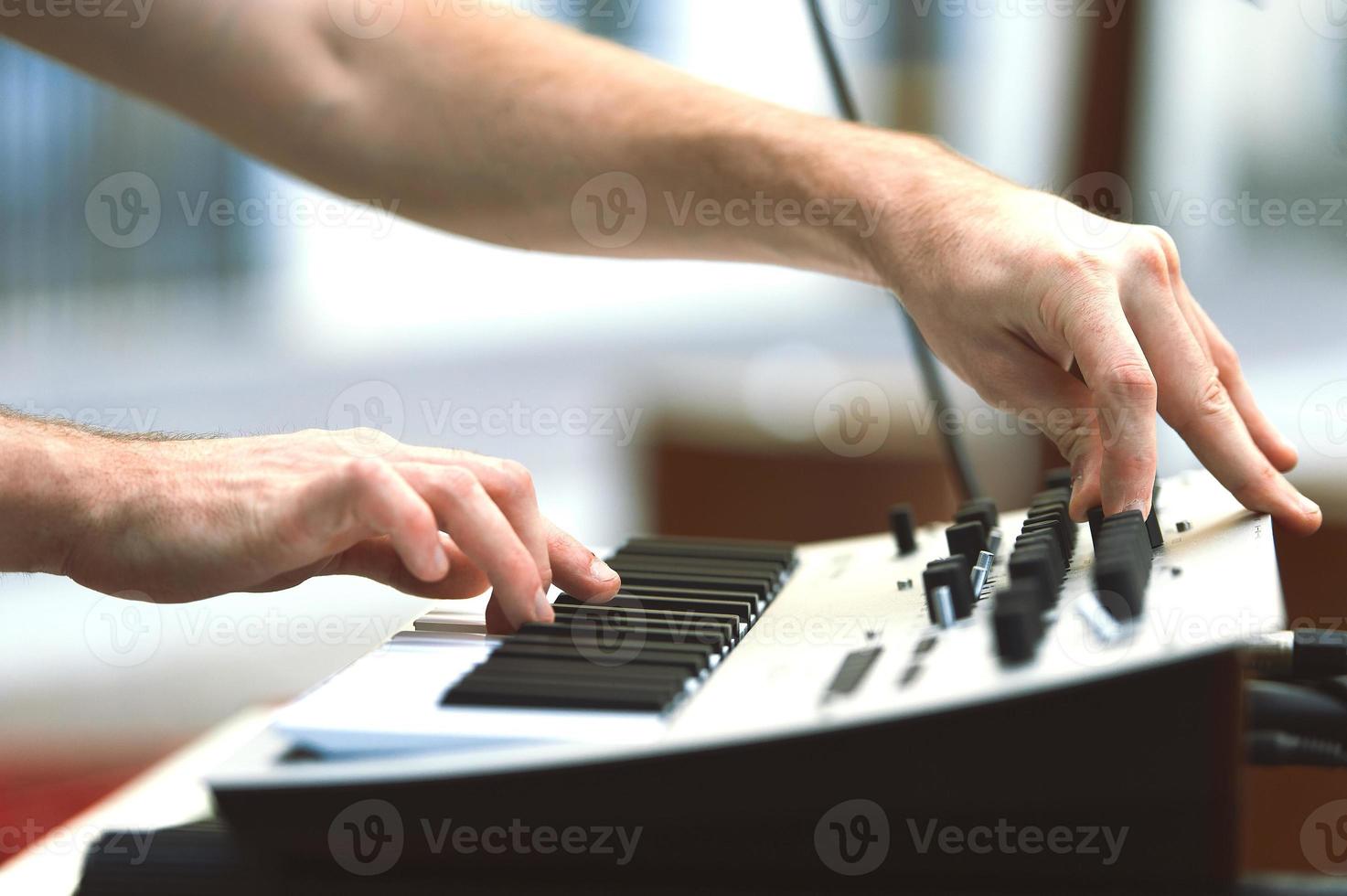 A synthesizer player during a concert moves knobs and controls the sound photo