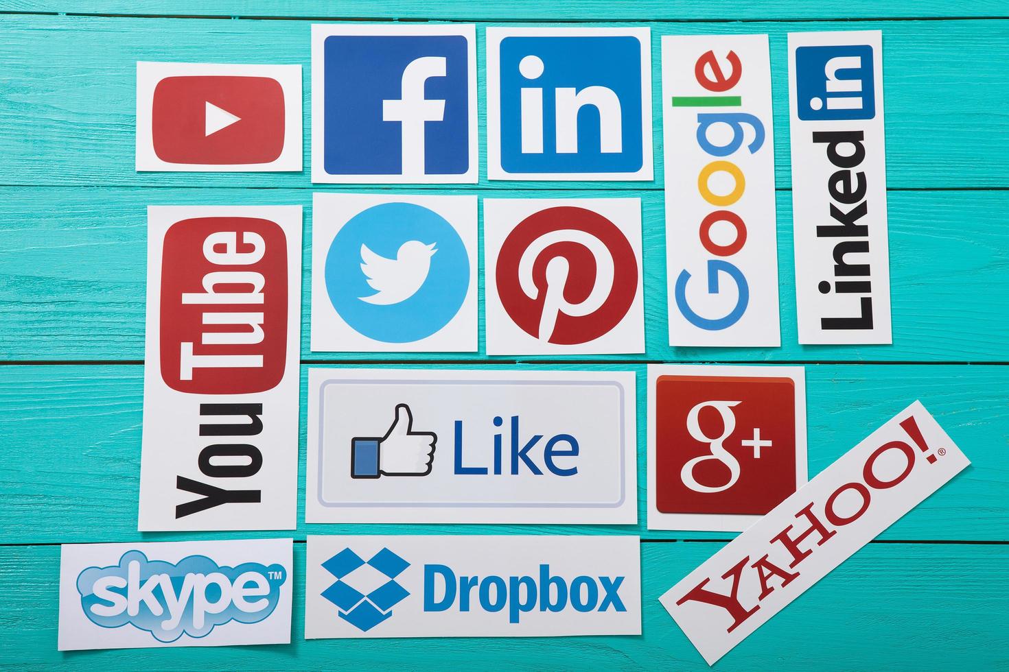 KIEV, UKRAINE - MARCH 10, 2017. Collection of popular social media logos printed on paper You Tube,Facebook, Twitter, Google Plus, Yahoo, Linkedin, Skype, Dropbox and like on blue wooden background. photo