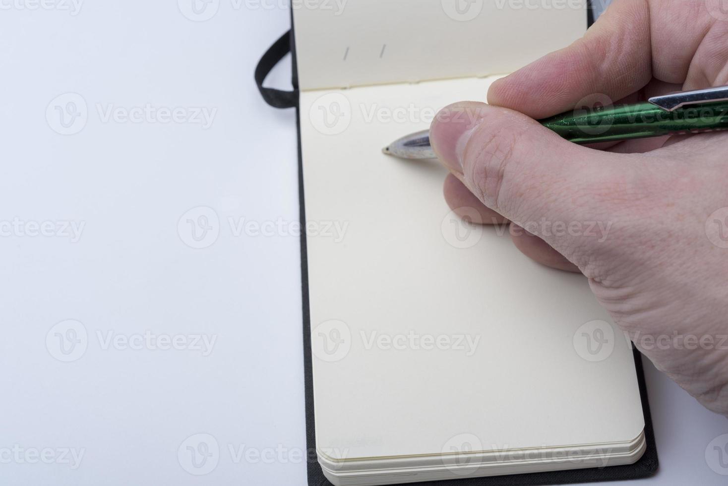 Hands of a man holding a notebook and a pen on a white background. photo