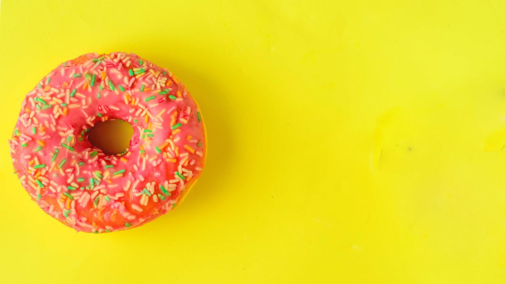 Pink donut on pastel yellow background. photo