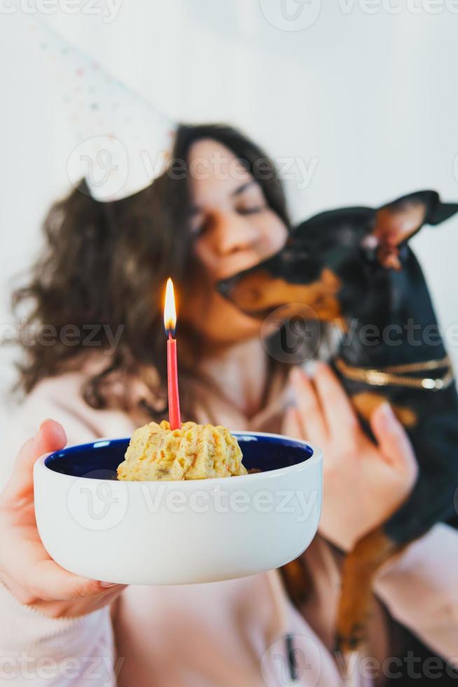 niña feliz dando pastel casero a su perro, en el interior foto