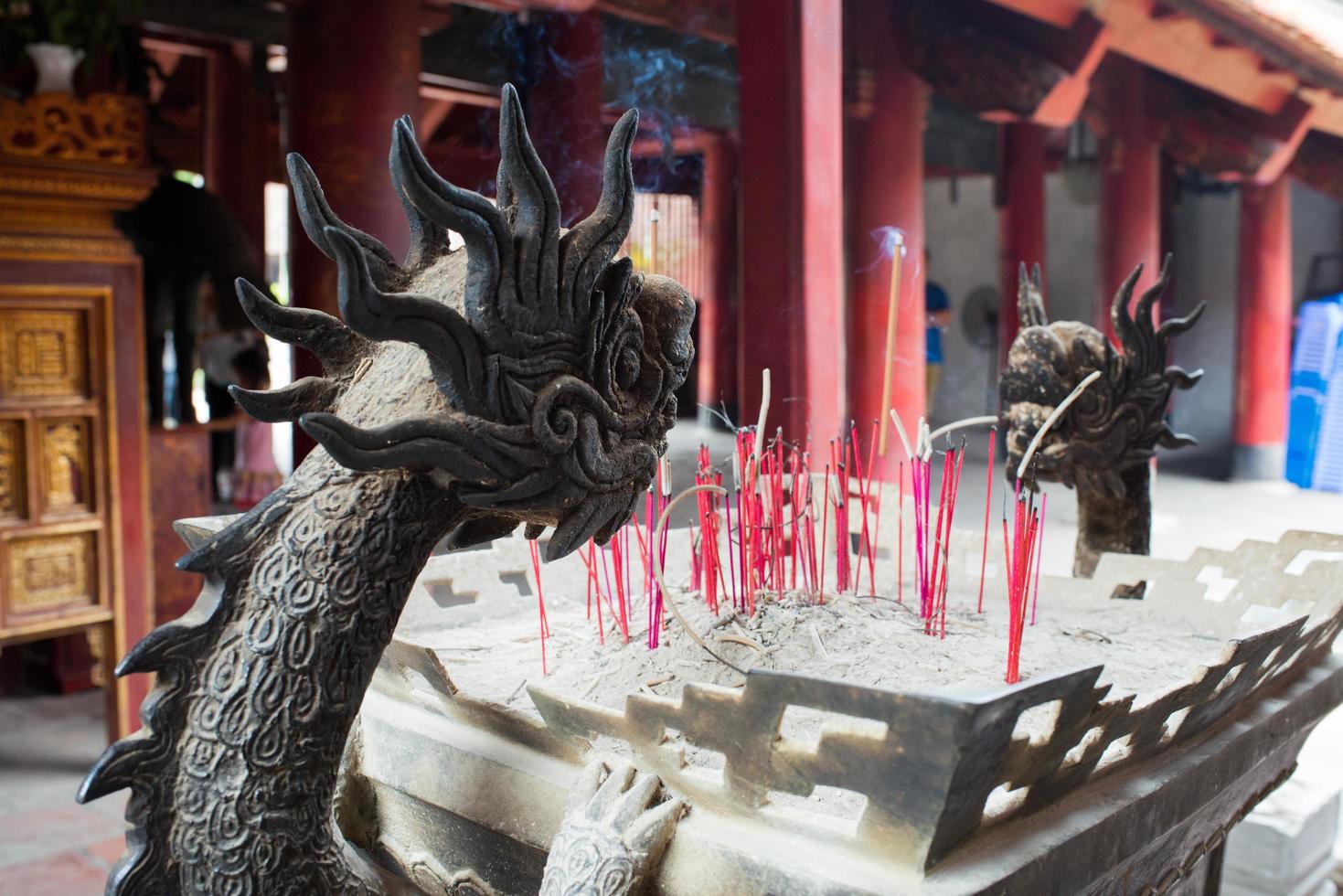 varitas de incienso ardiendo en un hermoso soporte con forma de dragón, ofrenda del templo en hanoi, vietnam. foto