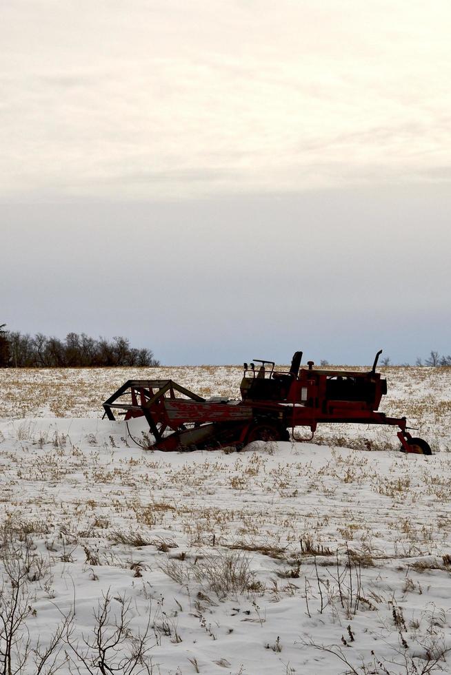 winter in Manitoba - a swather sitting in a snow covered field photo
