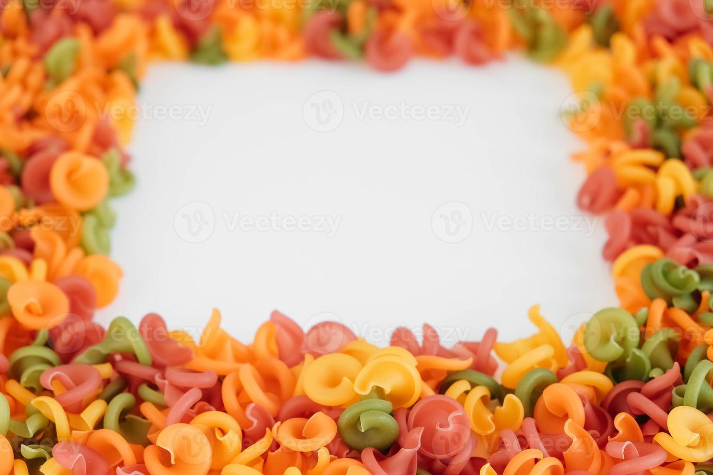 Multicolored pasta scattered on a white background in the form of a frame. Top view. Copy, empty space for text photo
