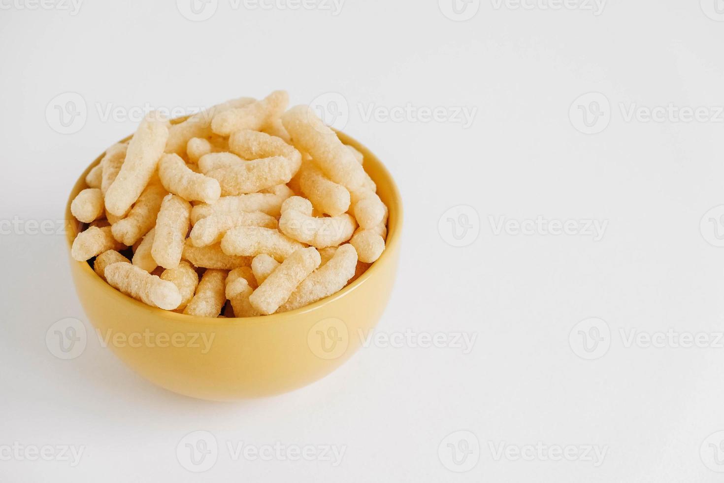 Corn sticks in a yellow bowl on a white background. Place for your text photo