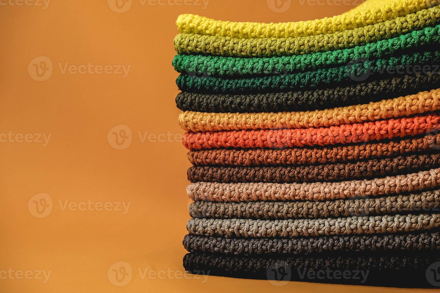 Stack of knitted material from multicolored threads on a orange background. Copy, empty space for text photo