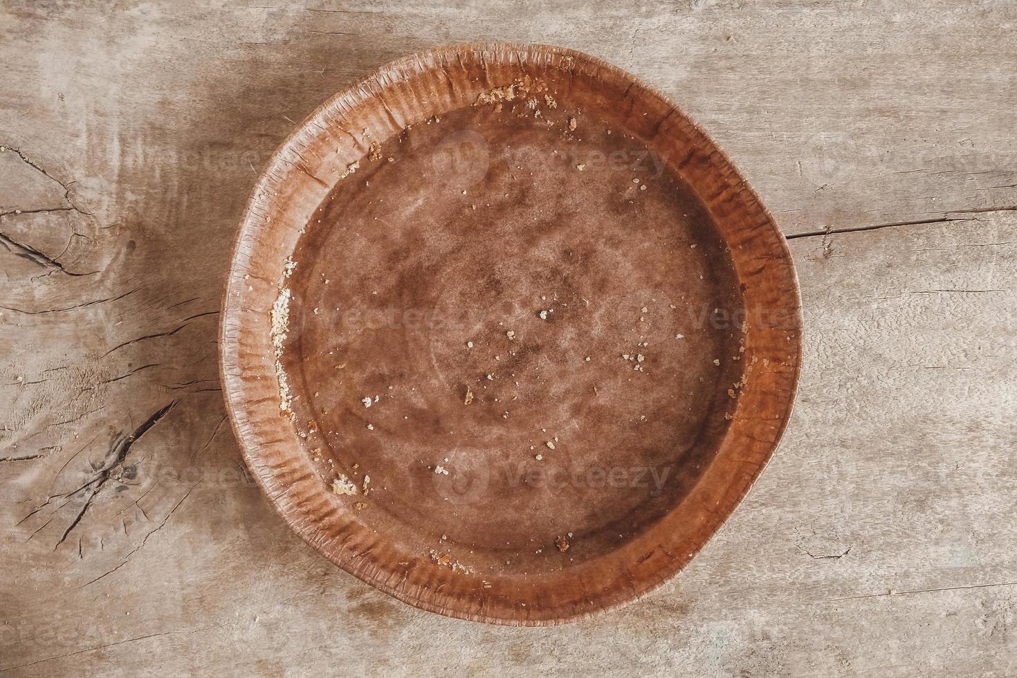 Paper craft plate with crumbs on vintage wooden background texture. Top view. Copy, empty space for text photo