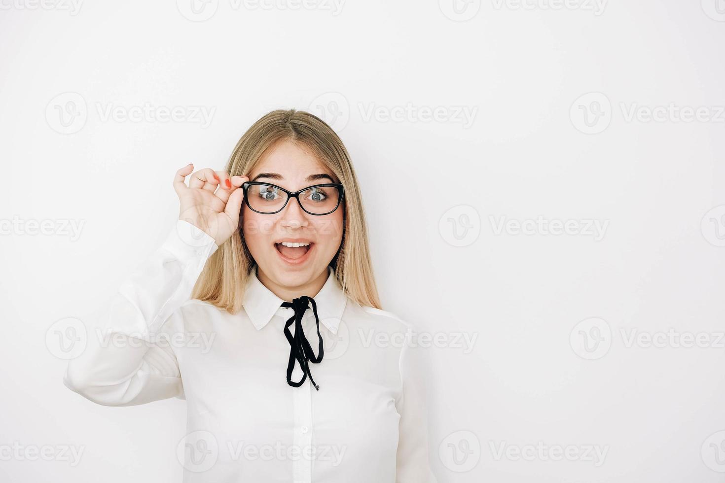 Portrait of a positive beautiful blonde woman wearing stylish white shirt holding her glasses on a white background. Copy, empty space for text photo