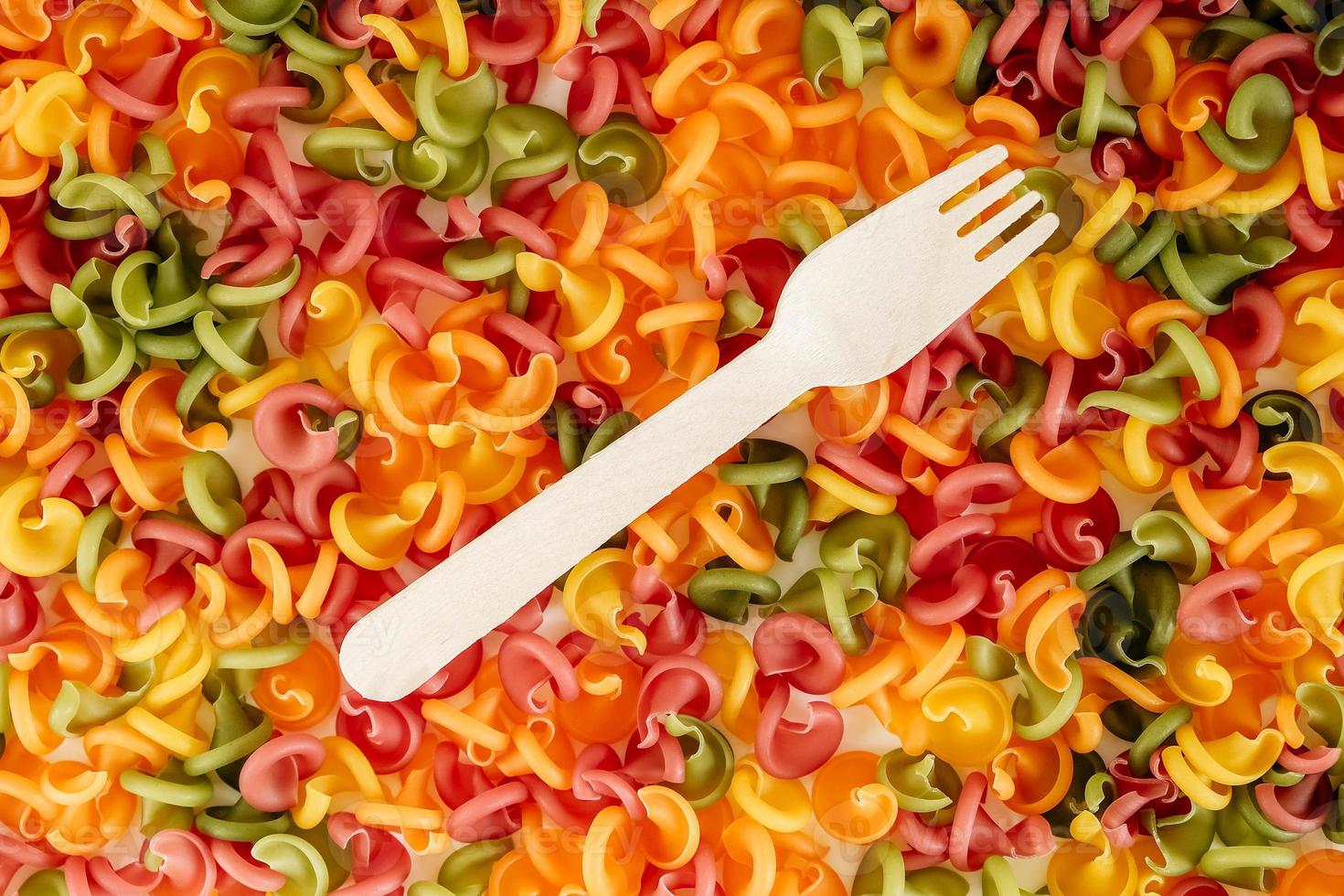 Multicolored pasta with a wooden fork as a background image. Top view. Copy, empty space for text photo