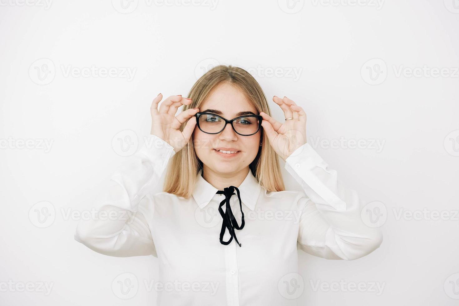 retrato de una hermosa mujer rubia positiva con un elegante pantalones blanco sosteniendo sus gafas sobre un fondo blanco. copiar, espacio vacío para texto foto