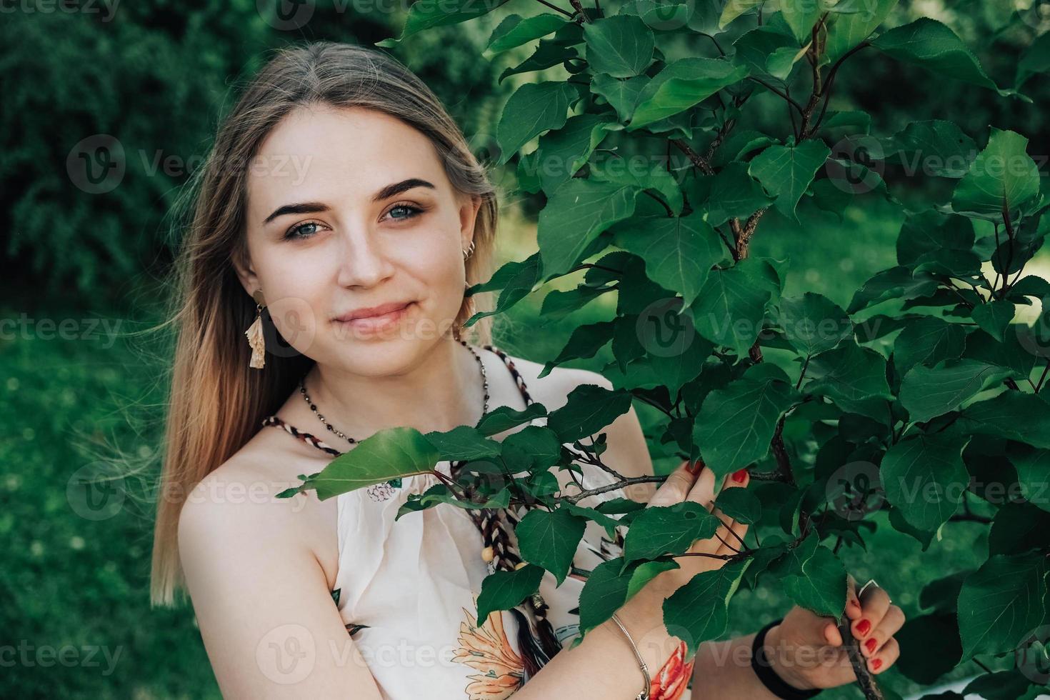 retrato de una hermosa chica rubia con belleza natural en árboles de hojas verdes. copiar, espacio vacío para texto foto