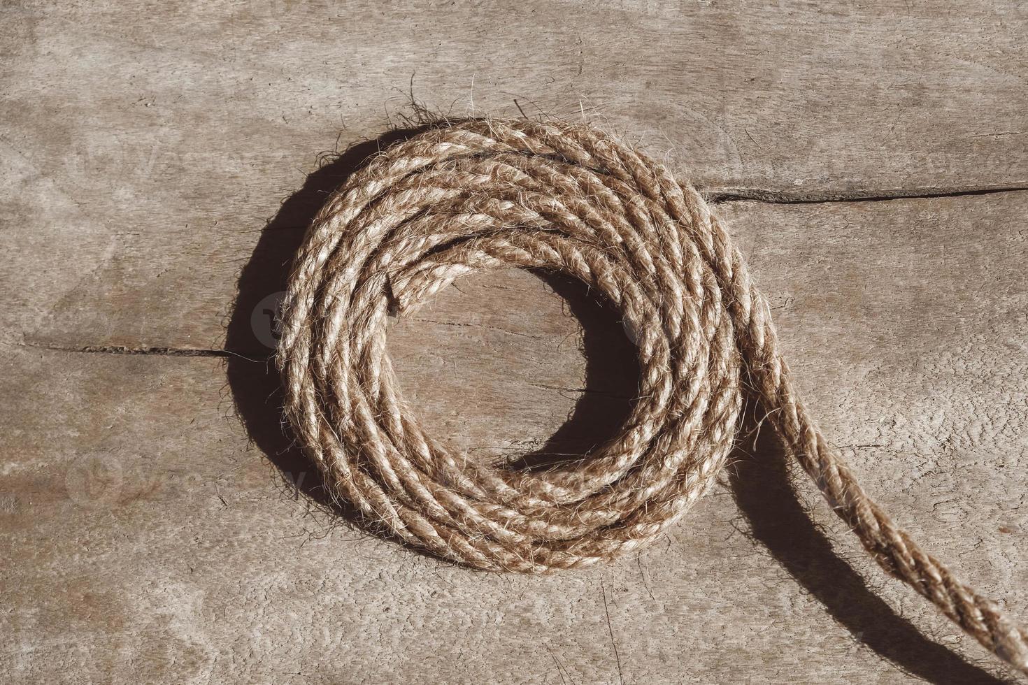 Thick rope on old wooden background. Top view. Copy, empty space for text. photo