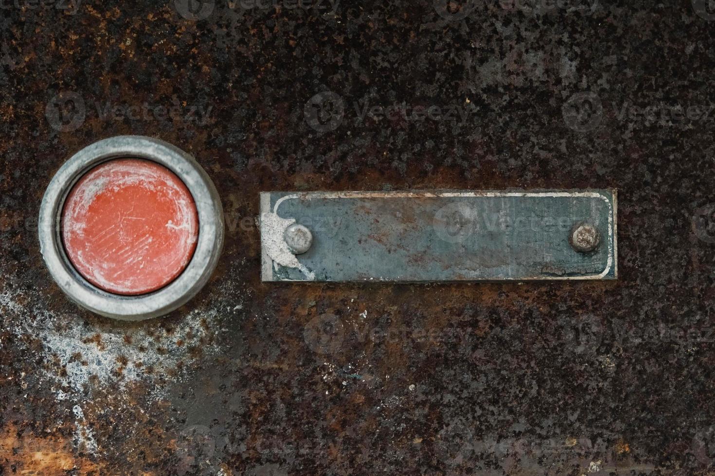 Old red button with a sign on a metal rust background. Copy, empty space for text photo